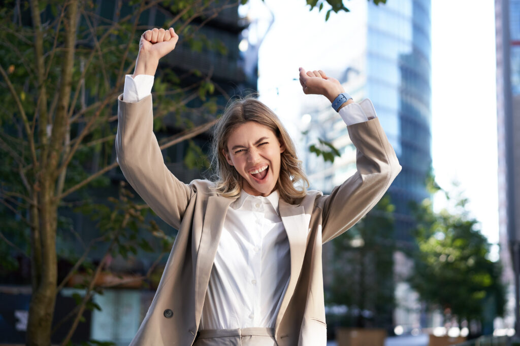 excited-businesswoman-screams-celebrates-lifts-hands-up-does-hooray-gesture-celebrates-victory-achieve-goal-stands-street-1024x683 MASTERING CONFIDENCE