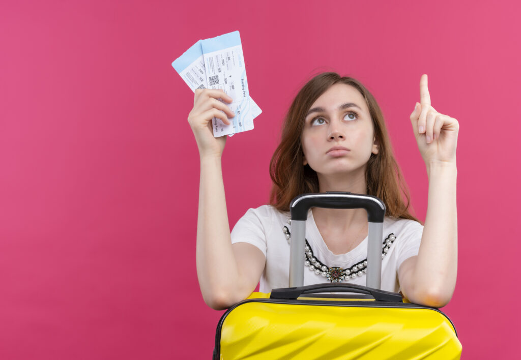 young-traveler-girl-holding-airplane-tickets-alarm-clock-with-suitcase-isolated-orange-wall-1-1024x708 Traveling on a Budget in the USA